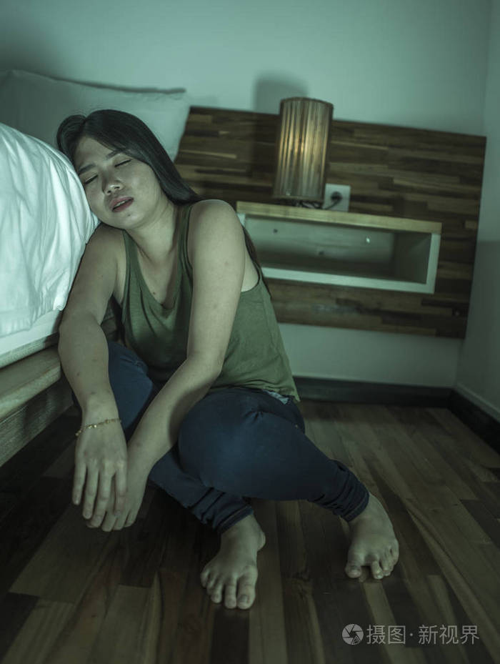 悲伤的亚裔韩国女子坐在床旁卧室的地板上患有抑郁症和焦虑症感到绝望