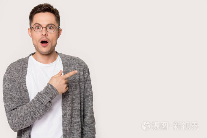 惊讶的男人张开嘴让大眼睛把手指指向一边
