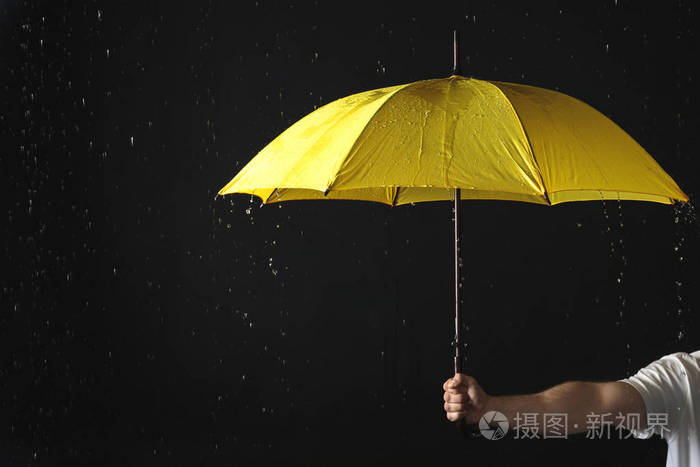 在黄色的背景下一个男人撑着雨伞