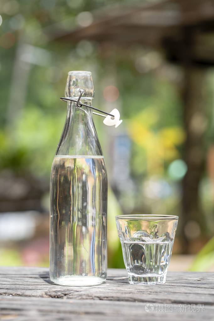 木桌上放有水的瓶子和玻璃杯
