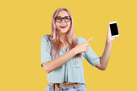 金发女人,粉红色的发胶,在明亮多彩的独立背景下摆姿势,拿着智能手机