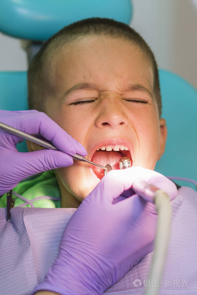 儿科牙医在牙科诊所的牙医椅子上检查一个小男孩的牙齿有牙医的孩子