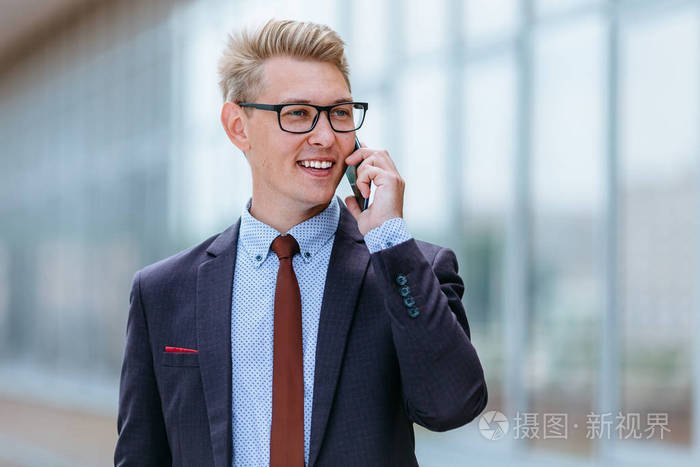 男执行经理穿着时髦的衣服在户外用智能手机.现代技术概念