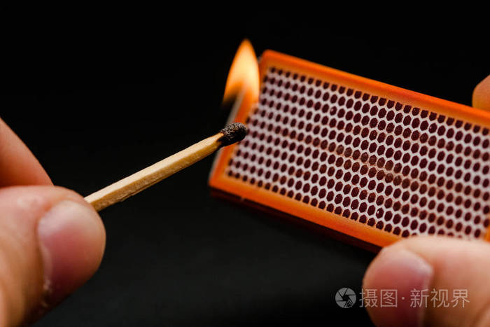 男人的手指点燃火柴点燃摩擦在黑色的背景上火柴和火抽烟