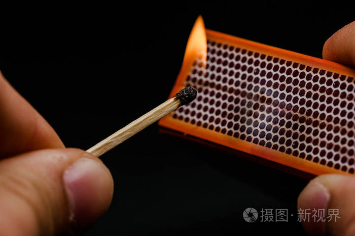 男人的手指点燃火柴点燃摩擦在黑色的背景上火柴和火抽烟