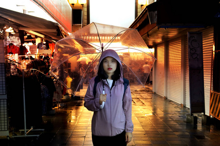 背包少女在雨中撑着透明的雨伞图片