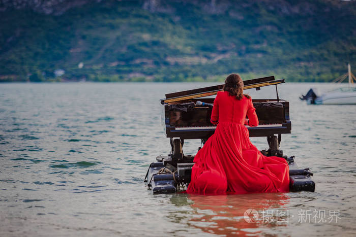 一个穿红色衣服的女人在湖边弹钢琴