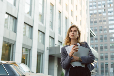 在城市商业中心附近,拿着咖啡,笔记本电脑和文件的职业上班族市中心.
