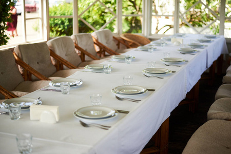 摆盘子摆着盘子和餐具的白色长桌.准备宴会,庆祝活动.照片