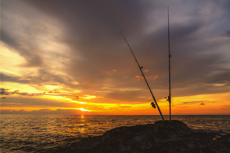 钓鱼竿在美丽的橙色海上日落的背景上.布吉岛,可可岛.傍晚.照片