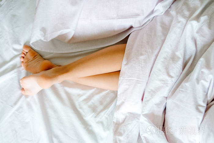 在室内光线明亮的白色床上脱毛后,女性拥有完美健康的丝滑腿皮肤.