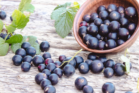 黑加仑子躺在木质背景上的绿叶旁.多汁的天然水果醋栗.照片