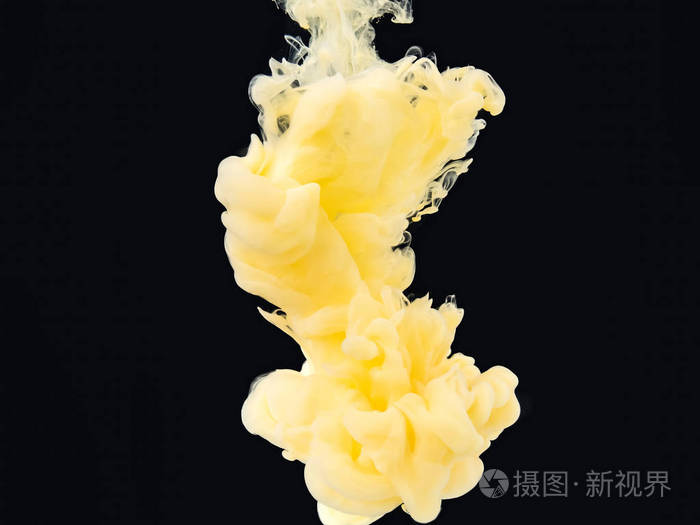 混合着液体的黄白色墨水云孤立在黑色背景上近距离观察与液体混合的