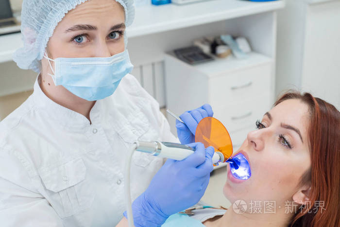 一位红发女病人龋齿的漂亮女牙医在牙齿上补牙
