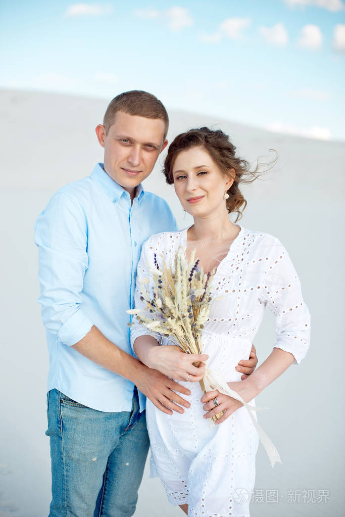 年轻的男人和女人拥抱在白色的沙丘上虚空中的爱情故事