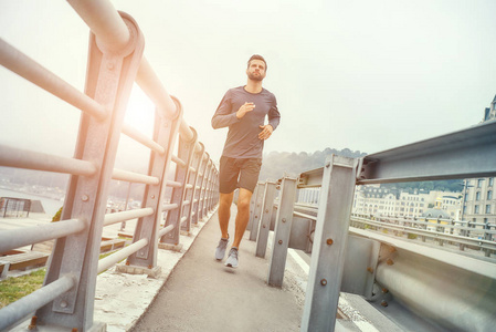 身着运动服的年轻健康男子在桥上慢跑照片