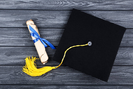 黑色木桌上有毕业证书的毕业帽图片