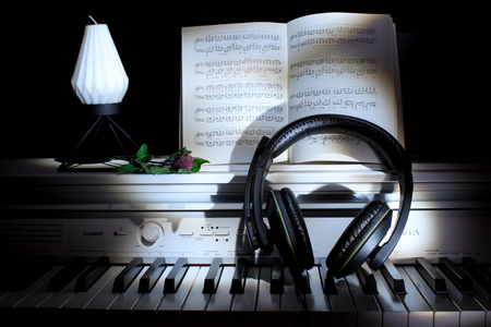 钢琴图片唯美意境钢琴键与音符和耳机在黑暗的背景下.音乐概念.