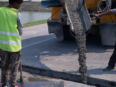 金属浇灌建筑工人在升级到住宅区街道时正在浇灌水泥.照片