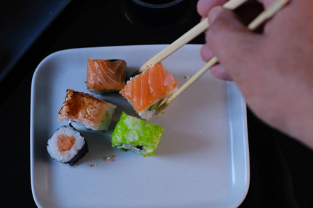 男人吃寿司卷三文鱼和飞鱼鱼子酱照片