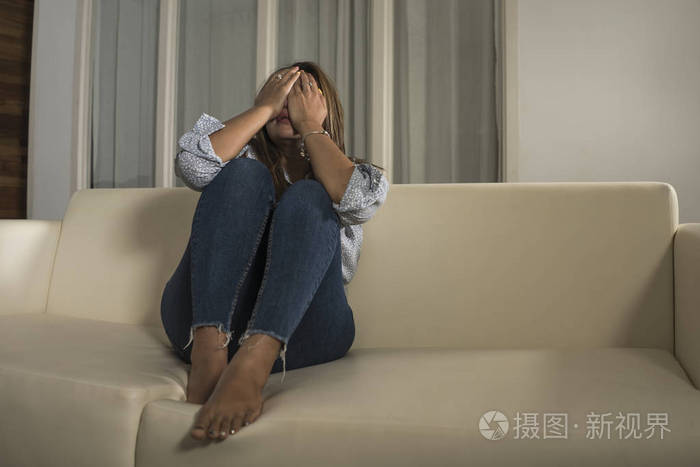 年轻悲伤沮丧的女孩在家里绝望地哭泣沙发上感到心碎遭受抑郁危机和