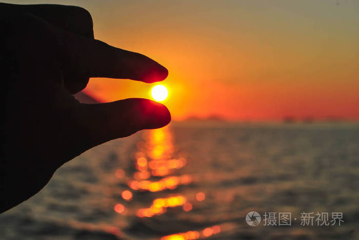 在美丽的夕阳下用手指托住太阳美丽的日落在热带科莫多岛纳闽巴乔弗雷