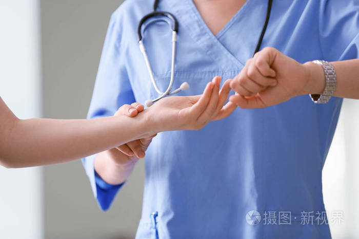 医生在临床上测量年轻女性的脉搏