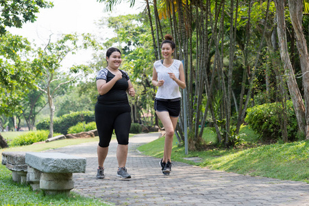模糊的胖女人和瘦女人在公园里慢跑锻炼,她们是为了健康而跑步减肥的