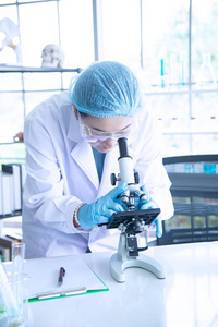 亚洲女科学家,研究员,技术员或学生利用显微镜进行研究或实验,显微镜