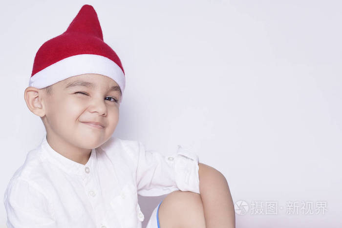 67岁的中东男孩戴着圣诞帽的肖像可爱的小男孩微笑着眨眼庆祝圣诞节