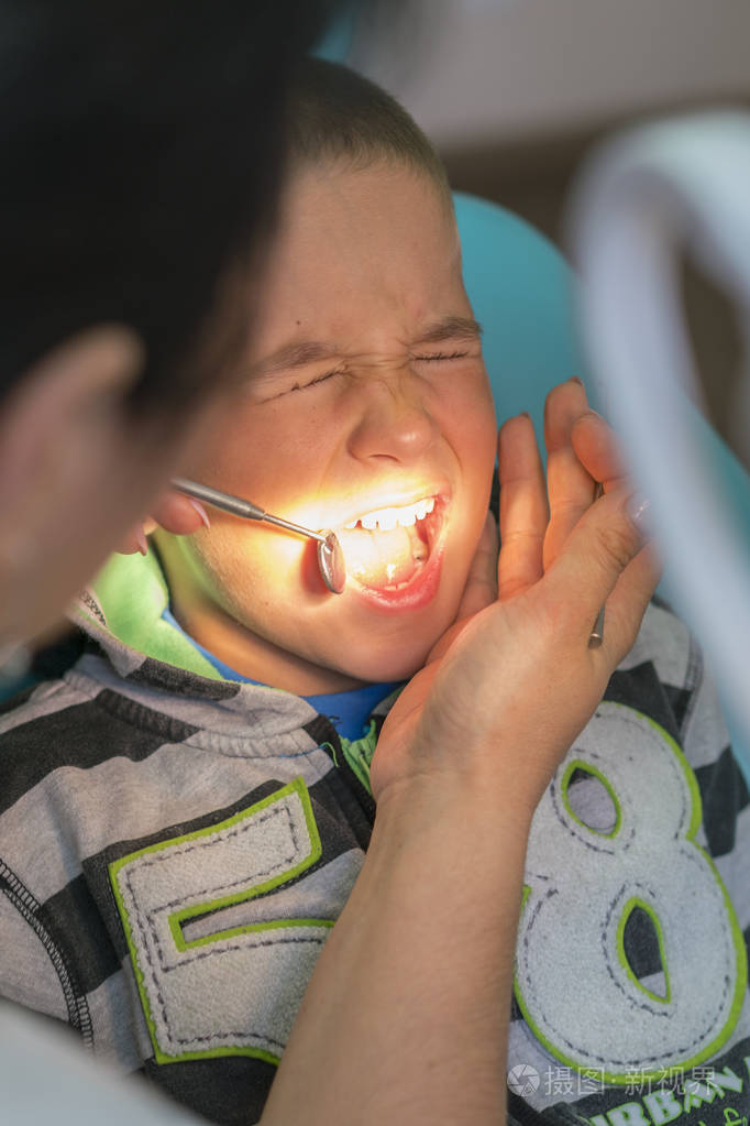 儿科牙医在牙科诊所的牙医椅子上检查一个小男孩的牙齿在牙科诊所和