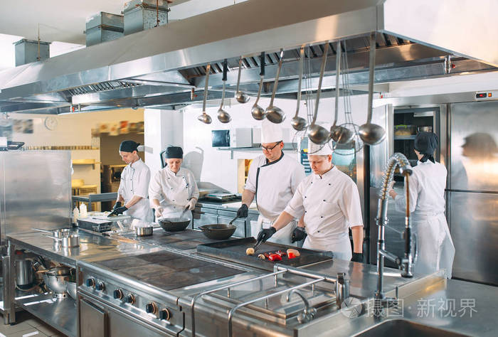 五个穿着制服的厨师在厨房里摆姿势