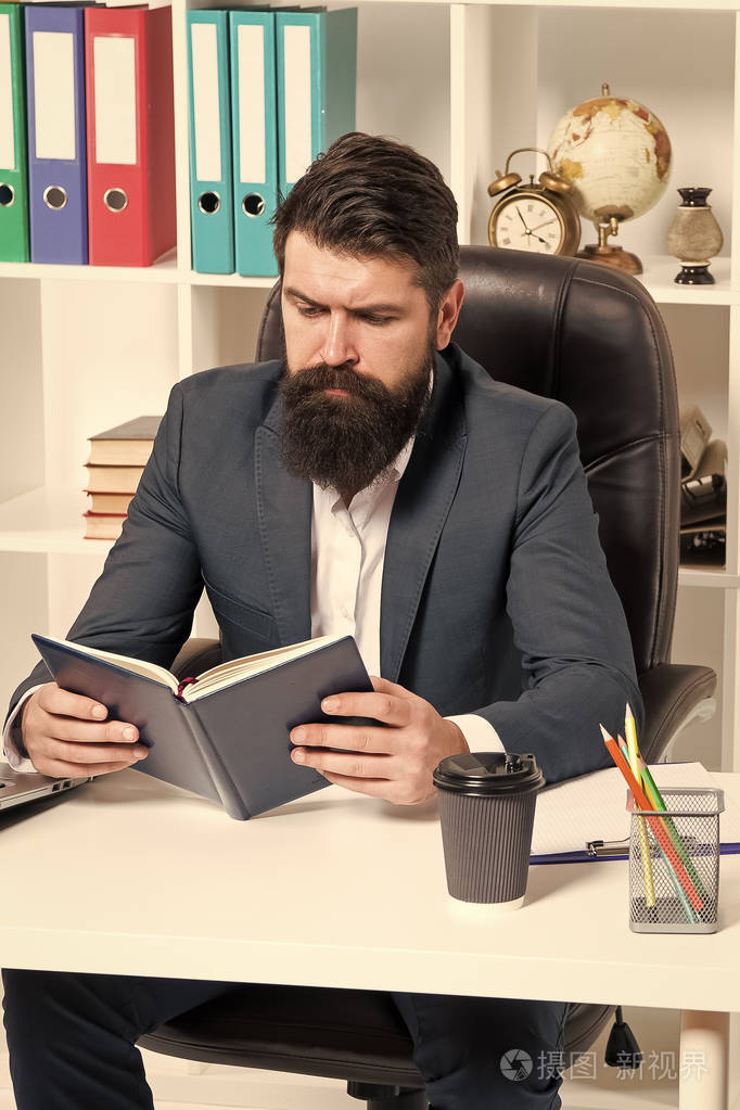 阅读权威商业书籍男人胡子时髦老板坐在扶手椅办公室内部看书工作场所
