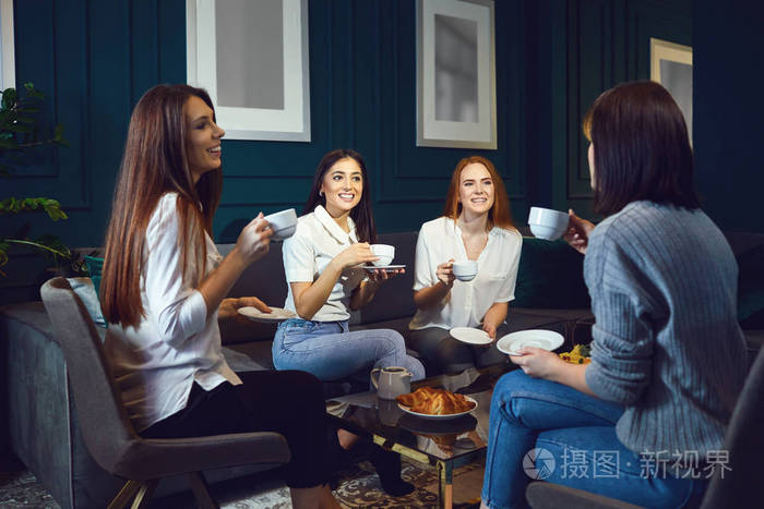 女人在家里的朋友聚会上笑着喝咖啡