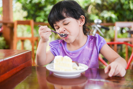 可爱的小女孩在吃蛋糕/亚洲孩子开心地拿着s照片
