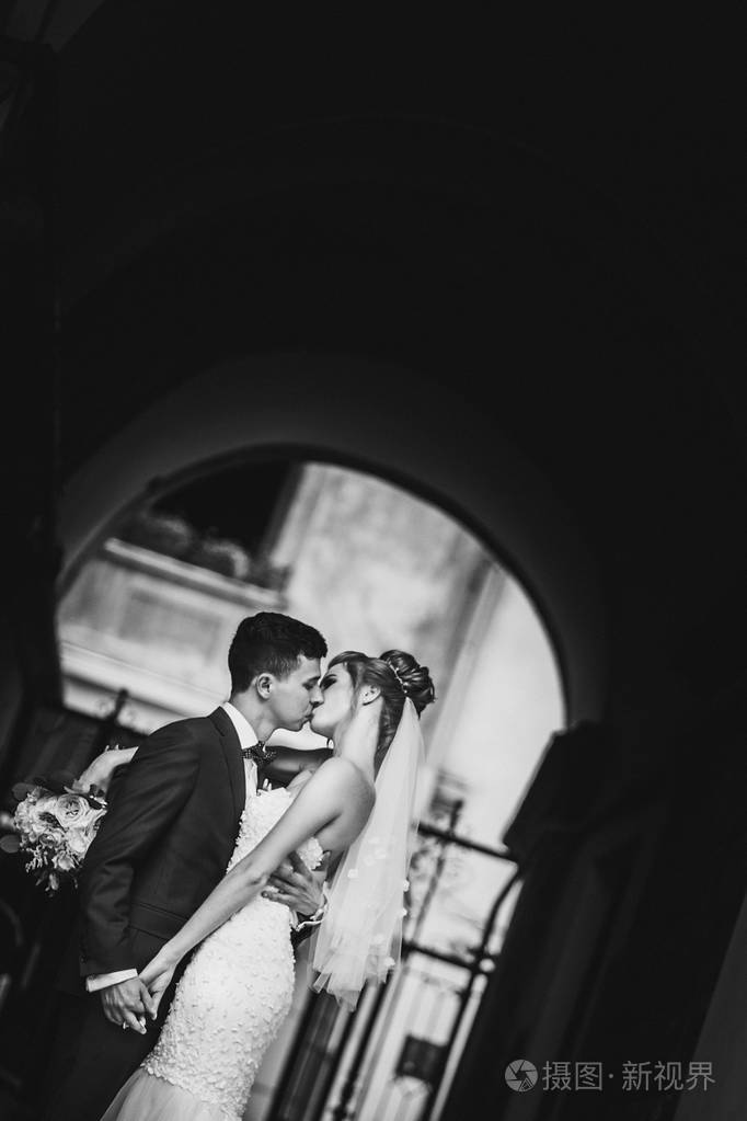 时尚新郎在阳光明媚的欧罗巴性感地亲吻他的幸福新娘照片-正版商用