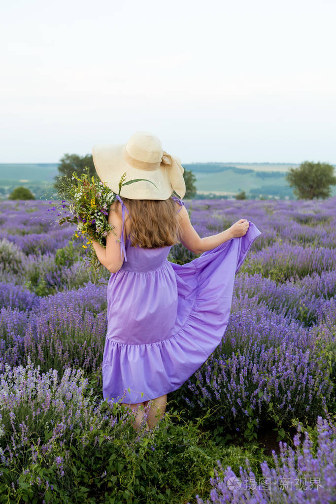 在薰衣草地里穿着紫色衣服戴着帽子的女人