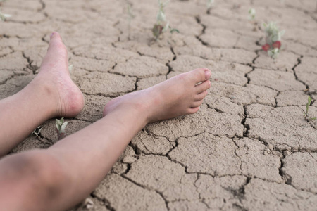 发烧晕倒,小孩脱水.孩子们的脚躺在干裂的泥土上.照片