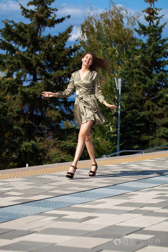 穿着绿裙子的年轻漂亮女人走在夏日的街道上