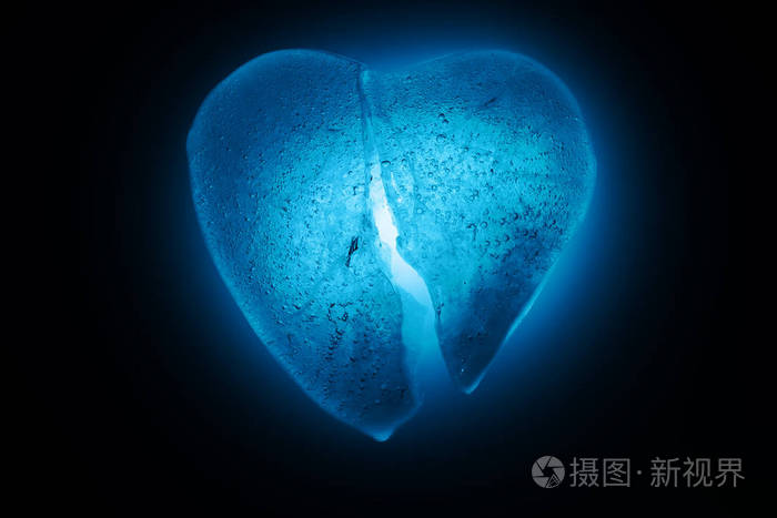 冰冻碎在半心象征蓝色特写在黑暗中在蓝色冷光中发光