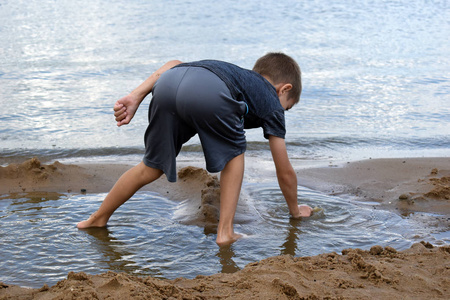 情绪活跃夏天男孩在河岸上玩泥巴.活跃儿童h照片