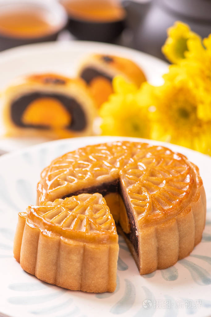 中秋节传统美食理念美丽的月饼在白色背景的蓝色图案板上加上花朵特写