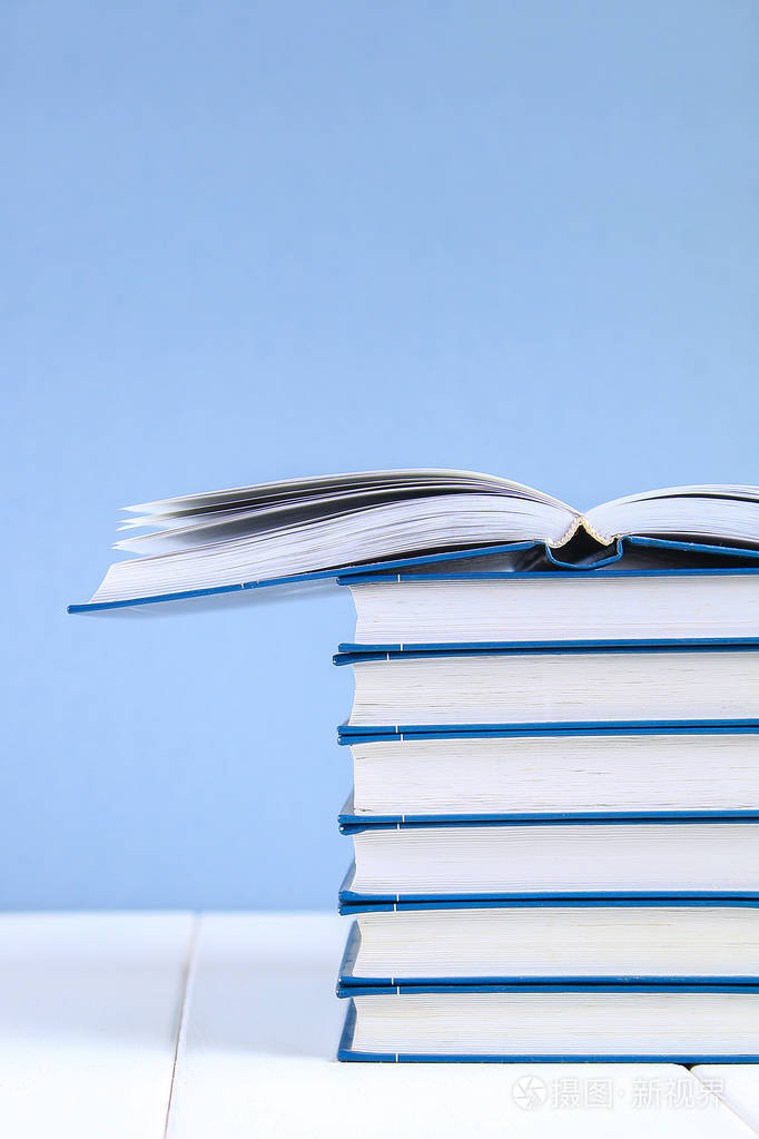 一摞蓝色背景的书一本藏在书堆上的书
