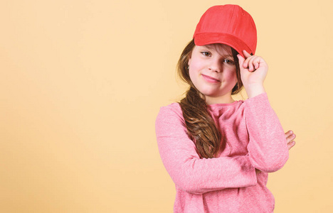 女孩可爱的儿童戴帽子或扣回帽米色背景.戴着明亮棒球帽的小女孩.