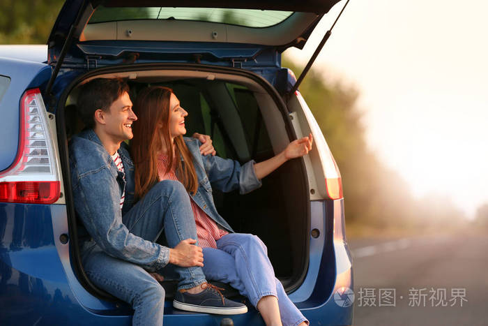 一对幸福的夫妇坐在乡下的新车后备箱里