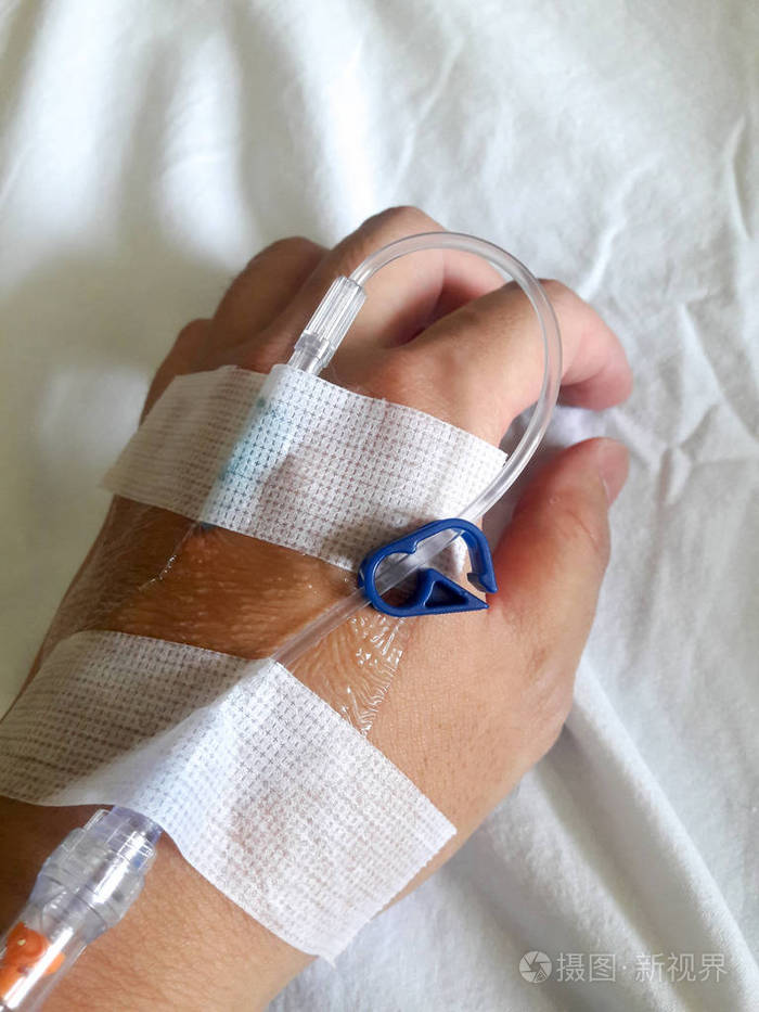 病人手拿着白布背景的生理盐水输液管