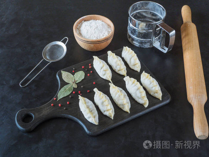 frozen uncooked dumplings on a black board.