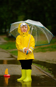 一个穿黄色雨衣的男孩在公园里散步.照片