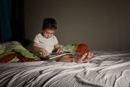男孩晚上在父母的床上看书照片