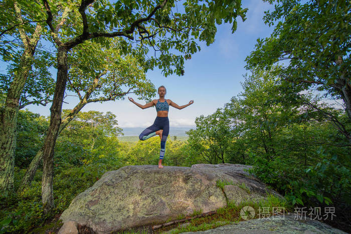 年轻女子站在树上练习瑜伽户外姿势与自然和谐